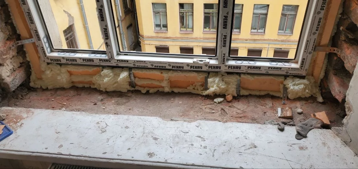 Низ окна: пластины, пена и кирпичное основание под рамой