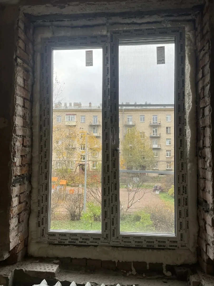 Двустворчатое окно в проёме, за стеклом двор и дома напротив, внизу радиатор