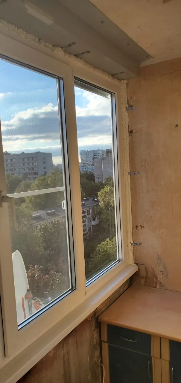 Две створки окна, пена по верху и анкерные пластины на стене