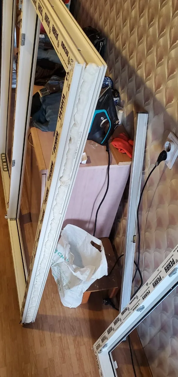 Рама с пеной по ребру у стены комнаты, рядом створка в плёнке